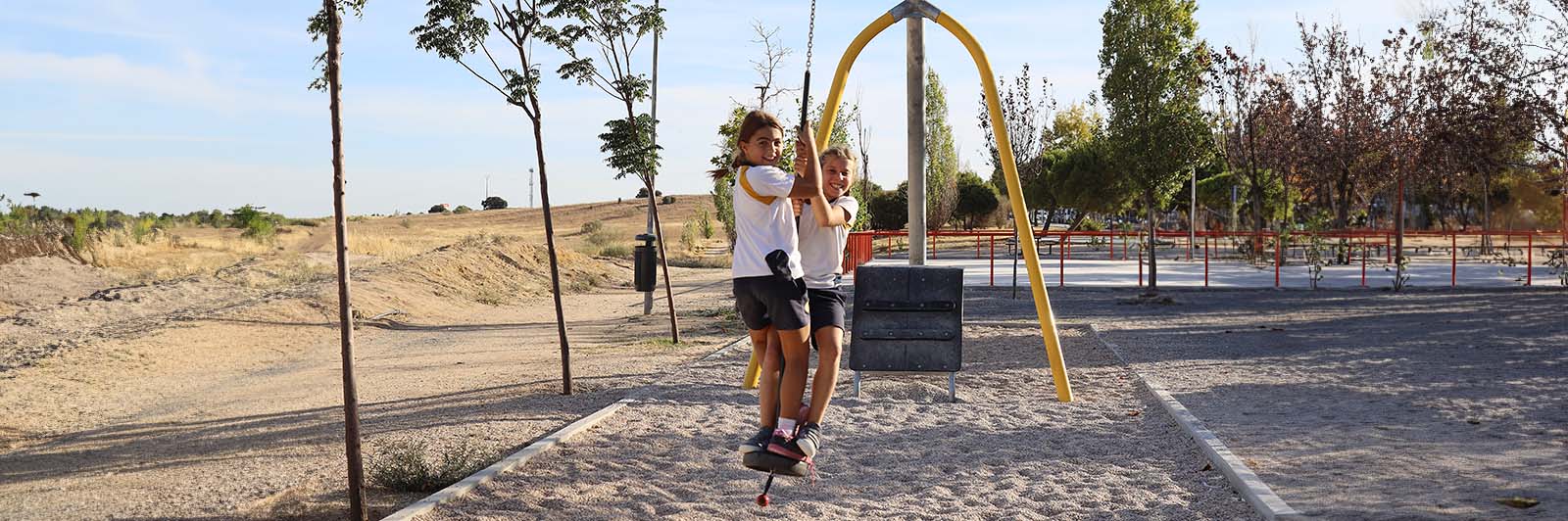 Children swing on an outdoor playground zipline.